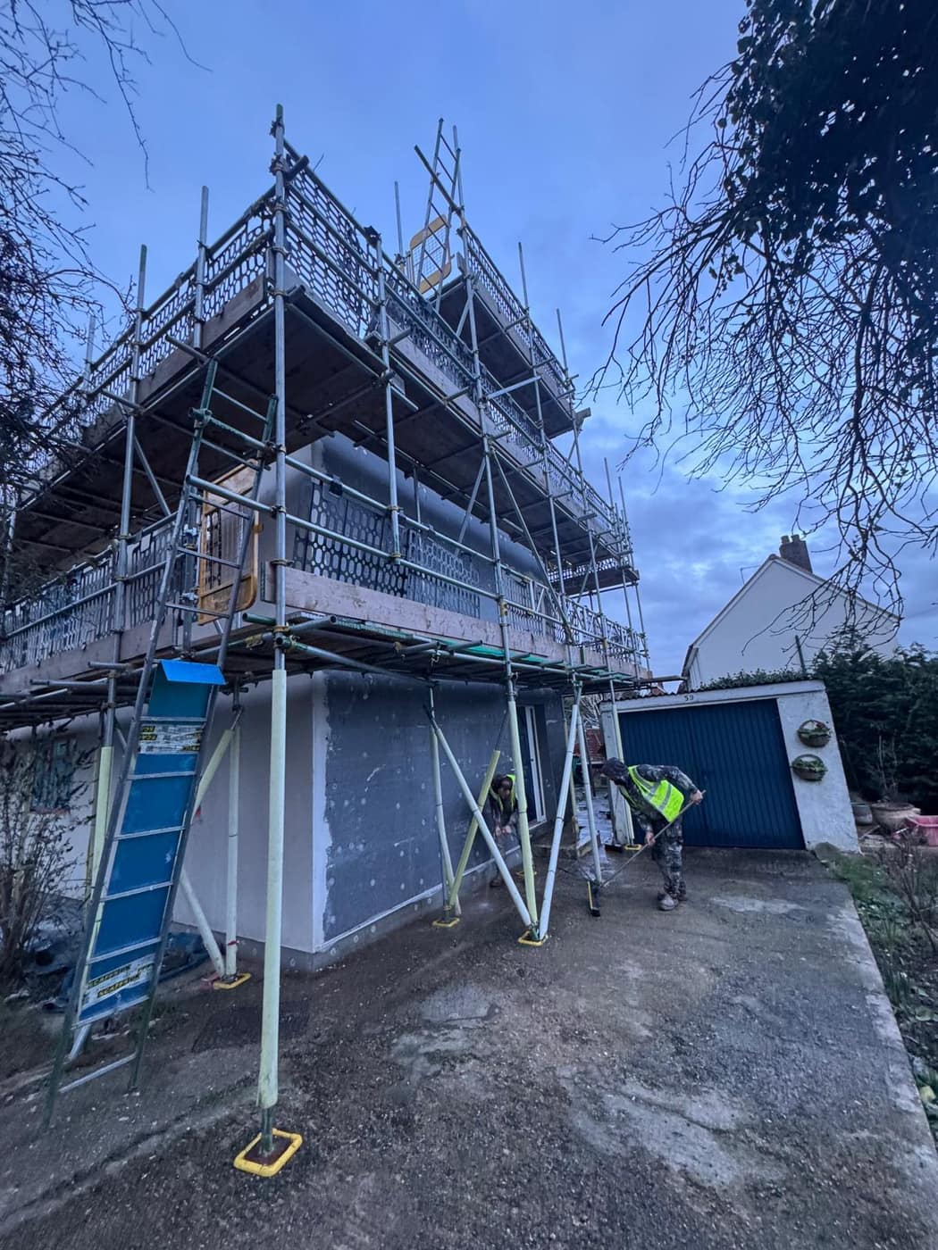 Insulation boards fixed to a house wall under scaffolding, basecoat going on
